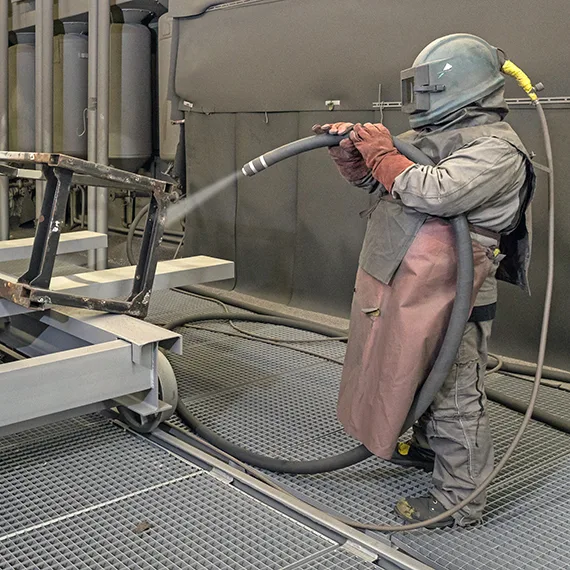 Sandstrahlen eines Bauteils im Werk